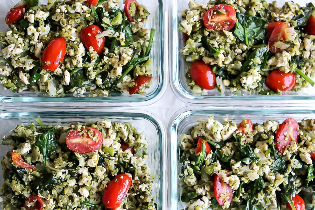 Four containers full of veggie packed tofu scramble made ahead and prepped for easy grab and go vegan breakfasts.