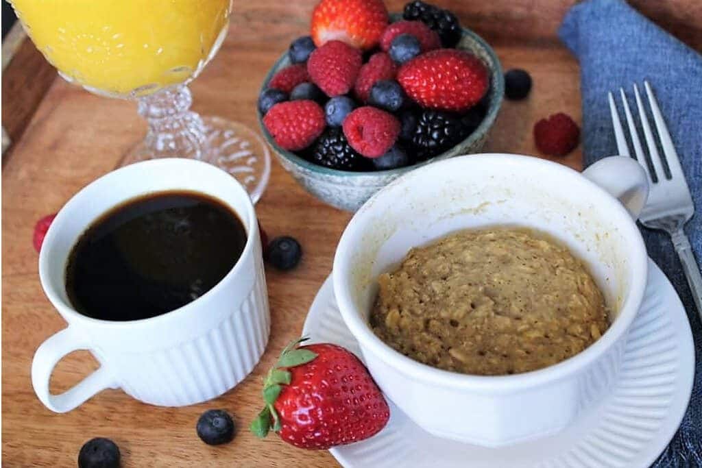 A vegan mug muffin on a breakfast tray with coffee and fruit.