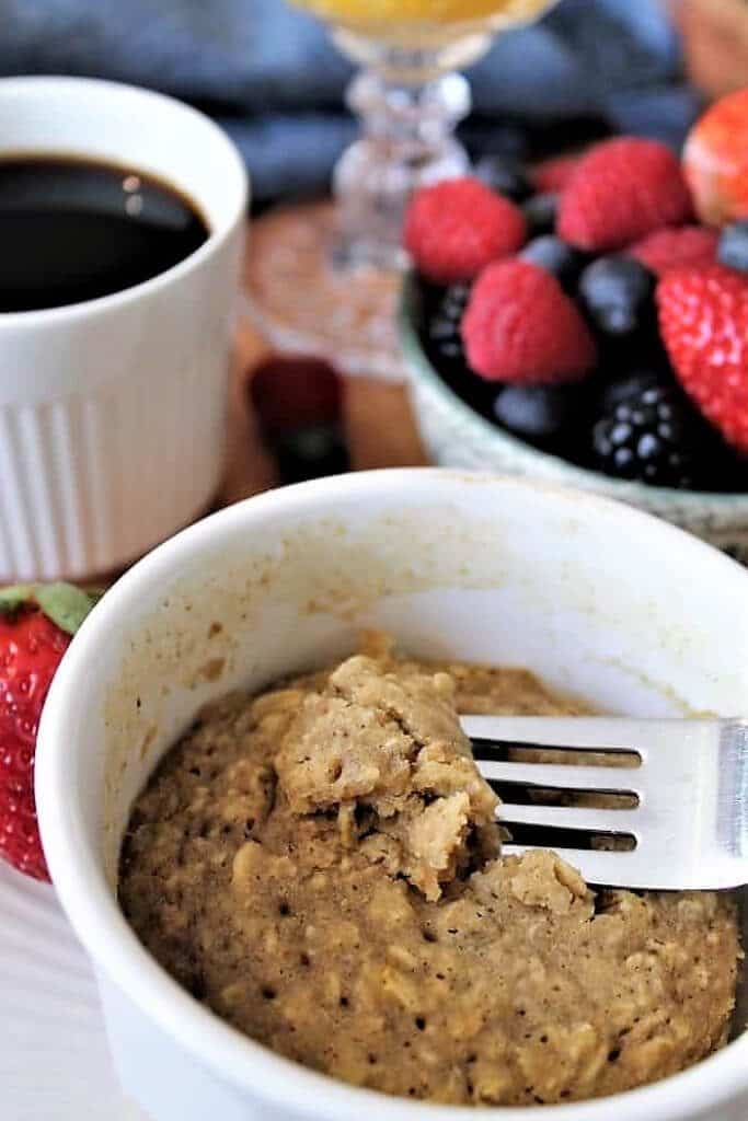 An oatmeal mug muffin with a fork taking a piece out of it.