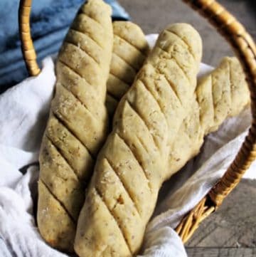 A bread basket with 4 vegan bread sticks with a blue napkin behind it.