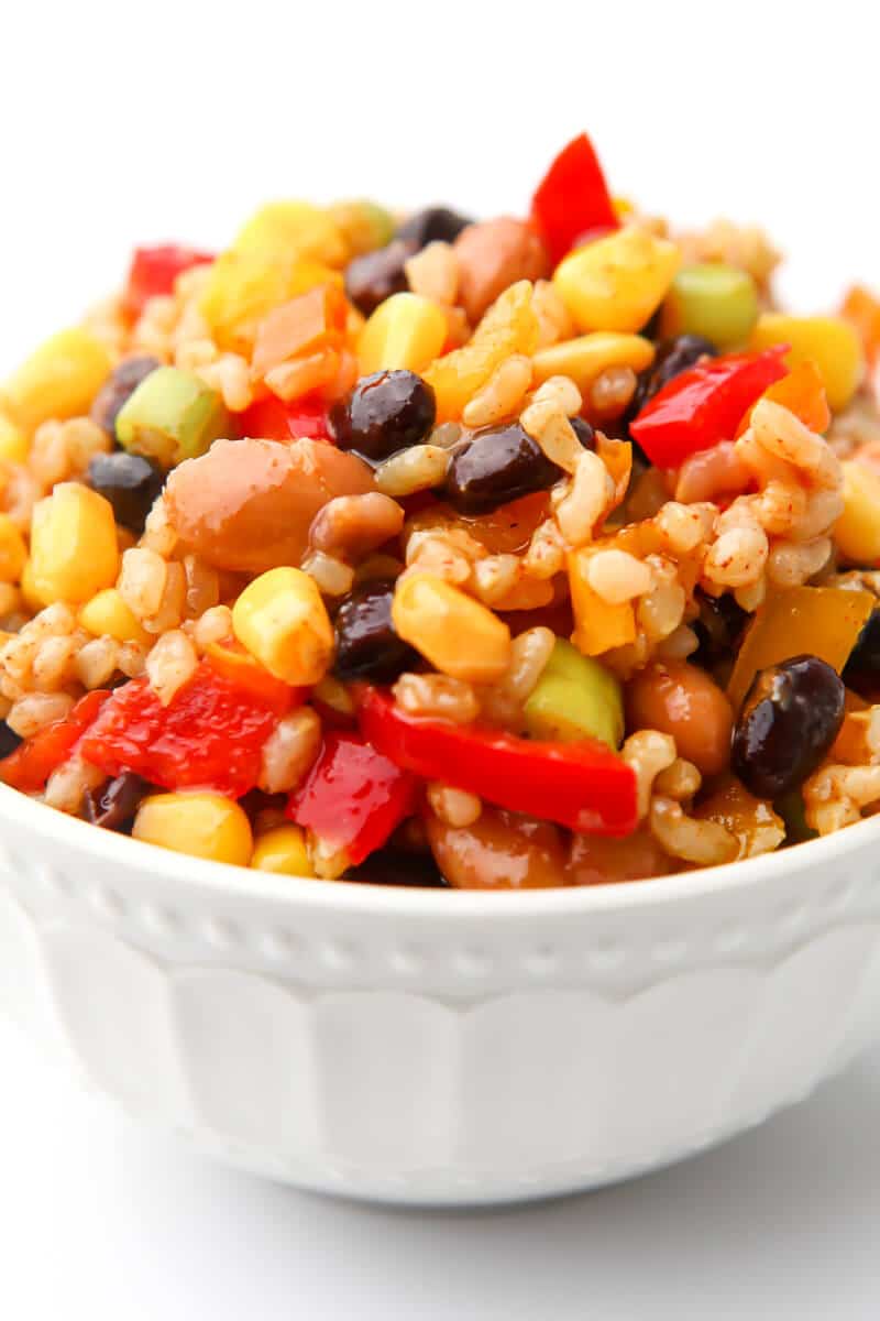 A bowl of bean salad made with black beans, pinto beans, bell peppers, corn, and short grain brown rice.