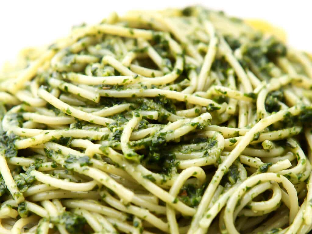 A pile of noodles with pesto on them.