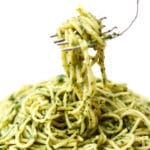 Noodles covered in vegan pesto with a fork lifting up some noodles.