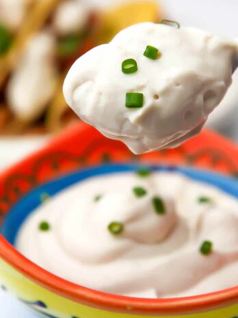 A bowl of tofu sour cream with a spoonful of it hovering over top of it.