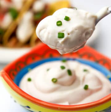 A bowl of tofu sour cream with a spoonful of it hovering over top of it.