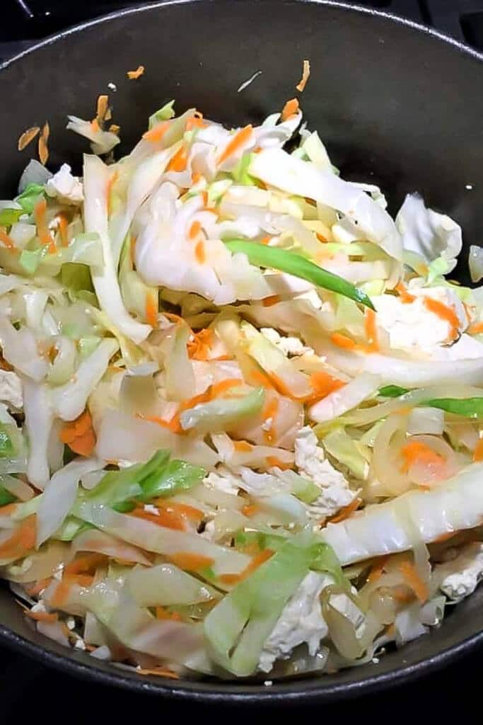 A pan of onions, cabbage and carrots frying in vegan butter to make Haluski.