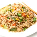 A close up of a plate of vegan fried rice with mixed veggies and tofu in it.