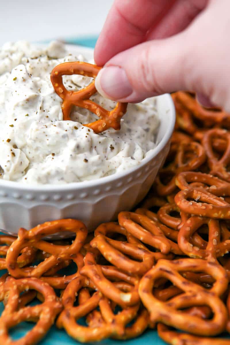 A white bowl of vegan clam dip with pretzels around it.