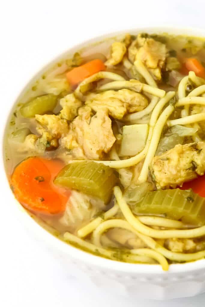 A bowl of noodle soup with carrots, celery, and vegan chicken.