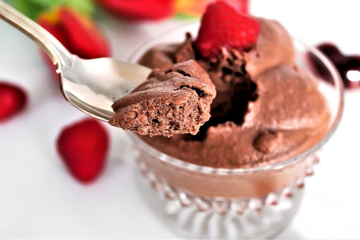 Vegan chocolate mousse with berries on top with a spoonful taken out.