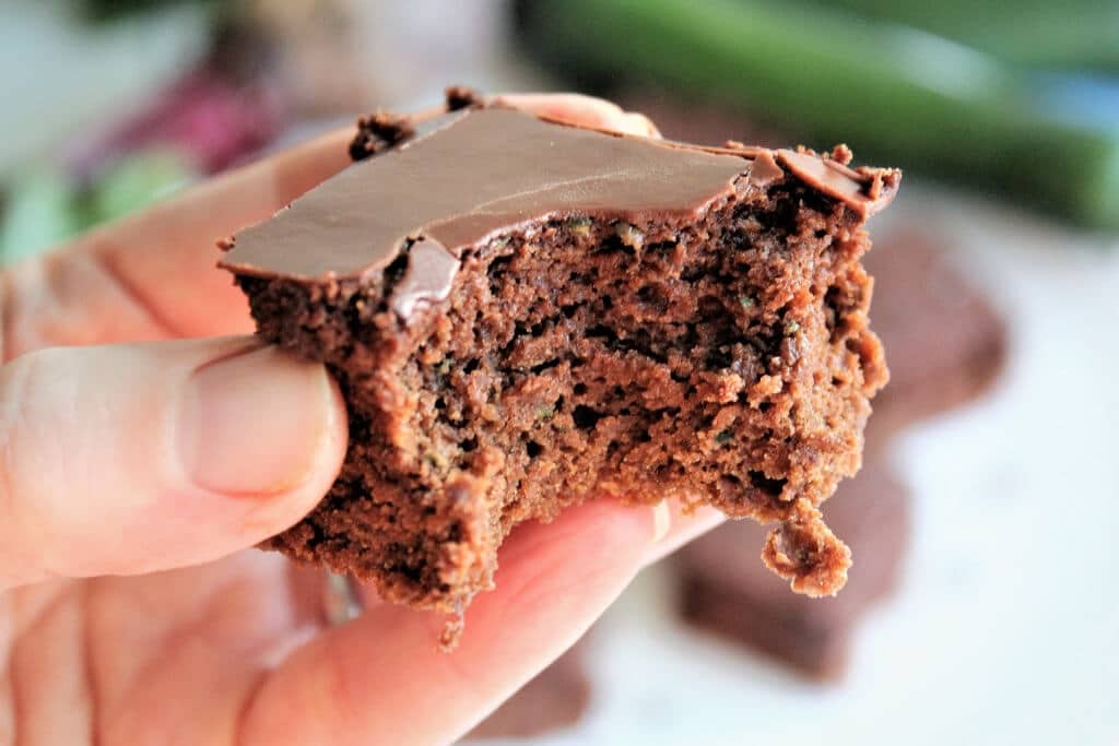 A vegan veggie brownie with a bite taken out of it with hidden zucchini and beets inside.