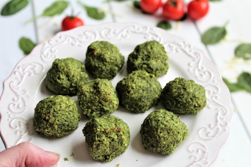 A white serving dish with hot gluten free vegan spinach balls.