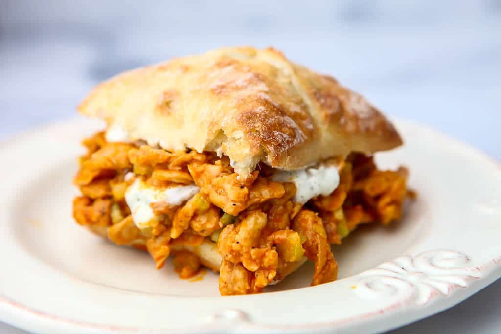 A vegan sandwich made with soy curls and vegan ranch dressing on a white plate.