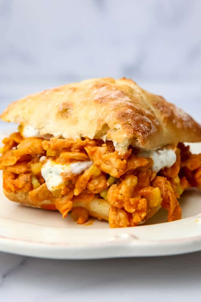 A vegan buffalo chicken sandwich on a white plate.