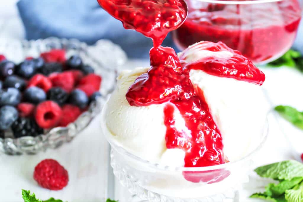 Raspberry compote being drizzled over vegan ice-cream