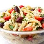 A bowl of vegan Greek pasta salad with a white background.