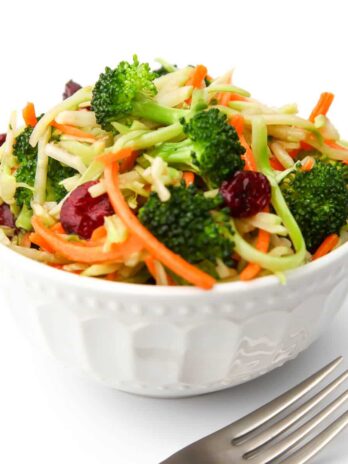 A bowl of vegan broccoli salad with cranberries with a fork on the side.