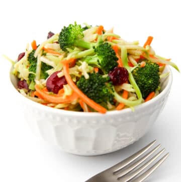 A bowl of vegan broccoli salad with cranberries with a fork on the side.