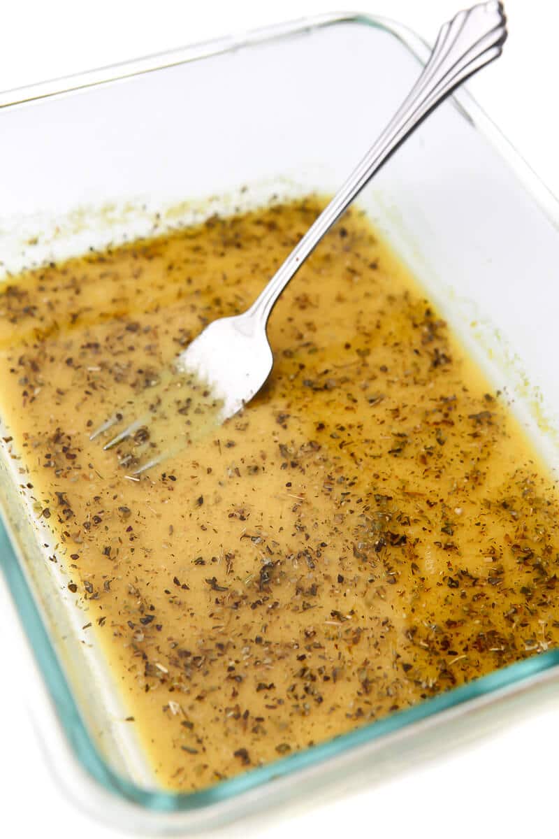 A feta cheese marinade in a shallow dish with a fork in it.