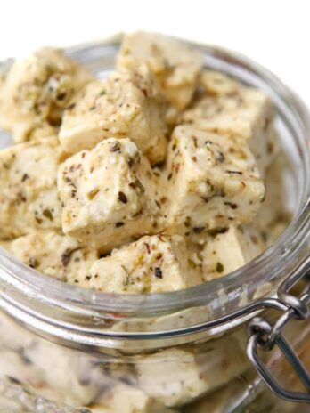 A close up of the top of a jar filled with tofu feta cheese.
