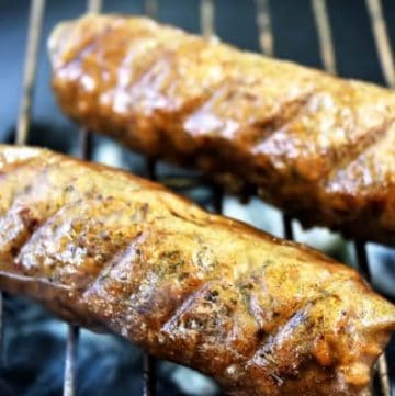Two gluten free vegan sausage links cooking on a grill.