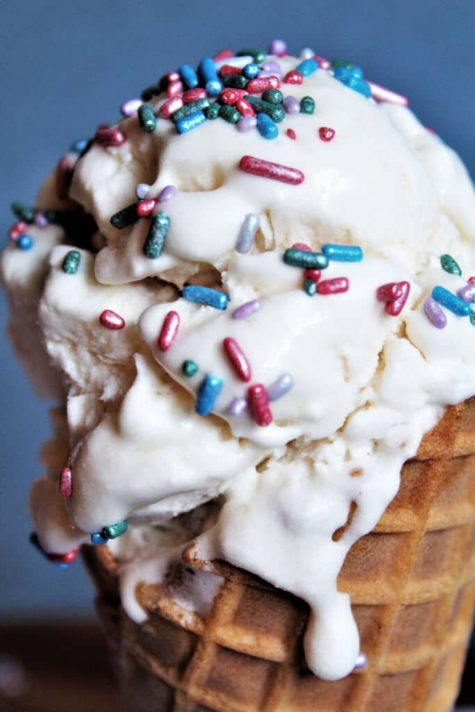 Vanilla aquafaba ice cream on a cone with sprinkles.
