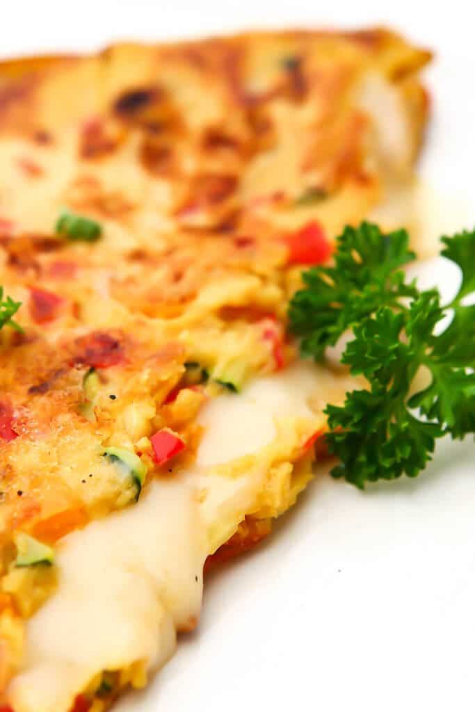 A close up of a chickpea omelette filled with vegan cheese.
