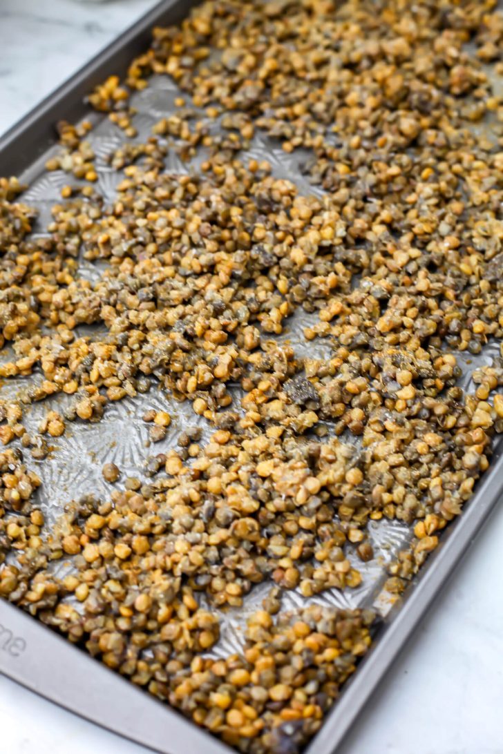 Green lentils on a baking sheet before roasting.
