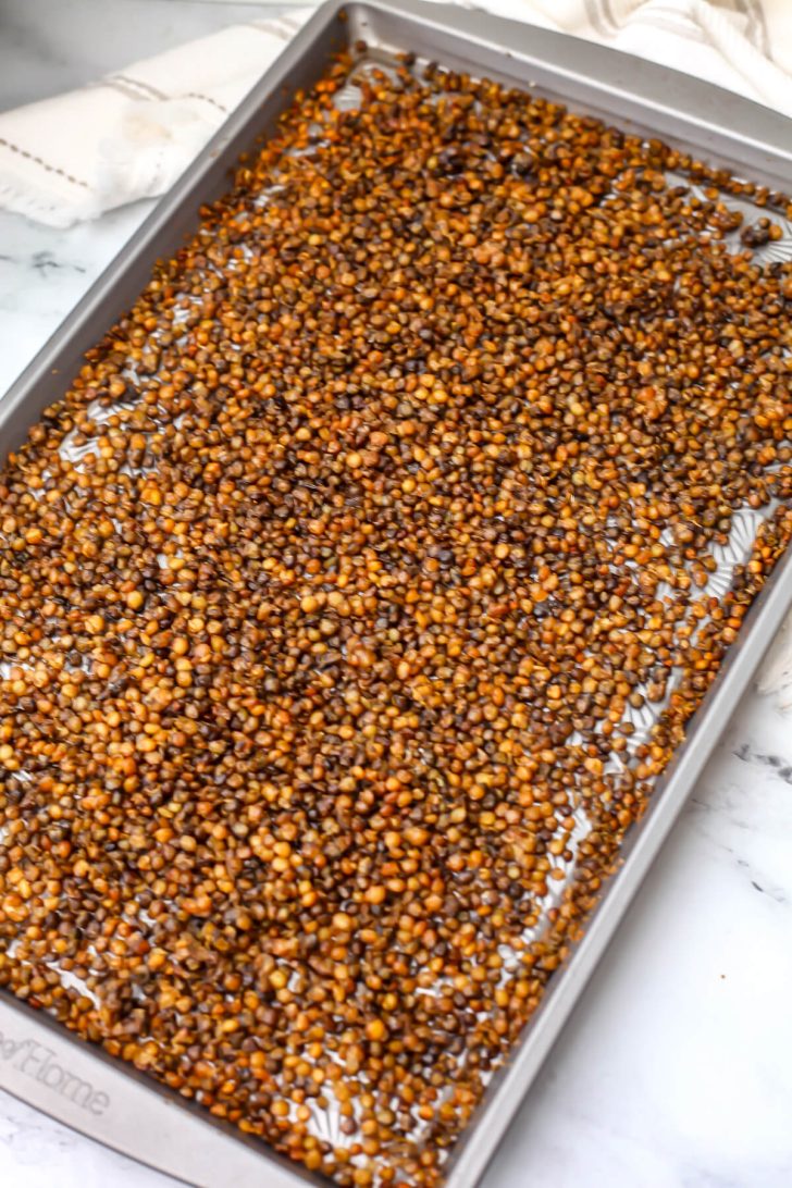 Green lentils on a baking sheet after roasting.