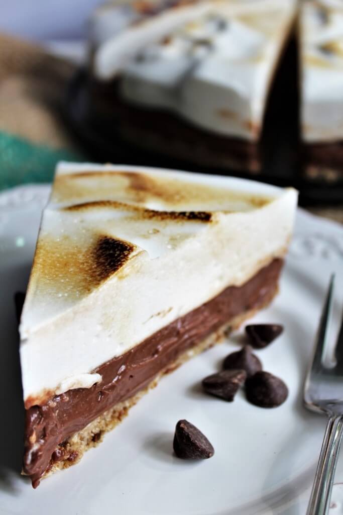 A slice of chocolate cream vegan s'mores pie with chocolate chips next to it.