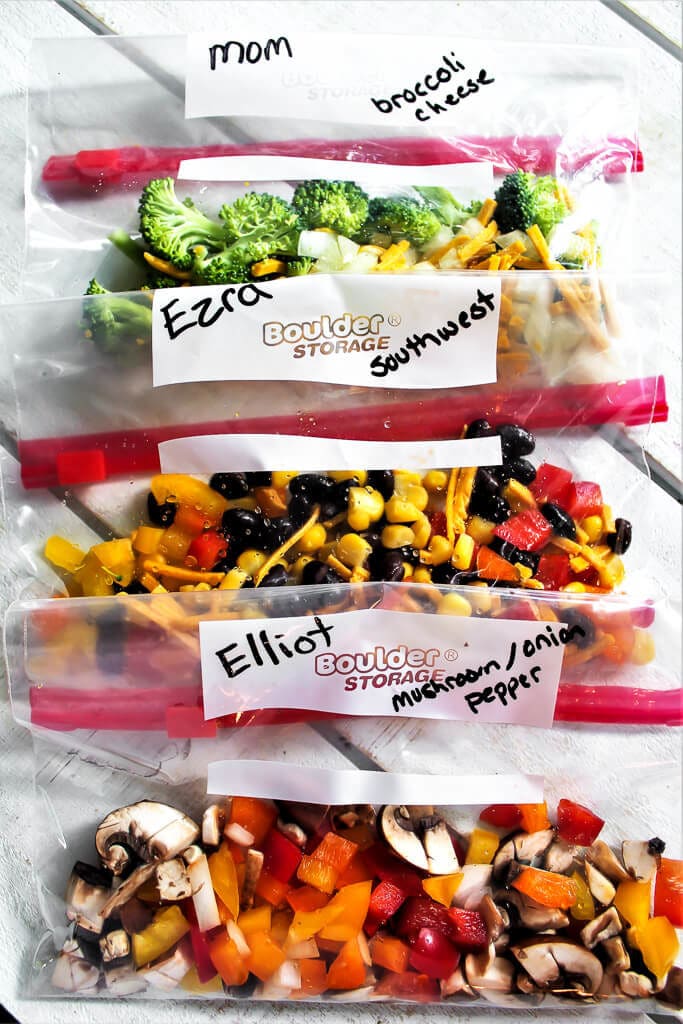 Three sandwich bags with veggies in them before pouring in the chickpea flour mixture to make vegan camping omelettes.