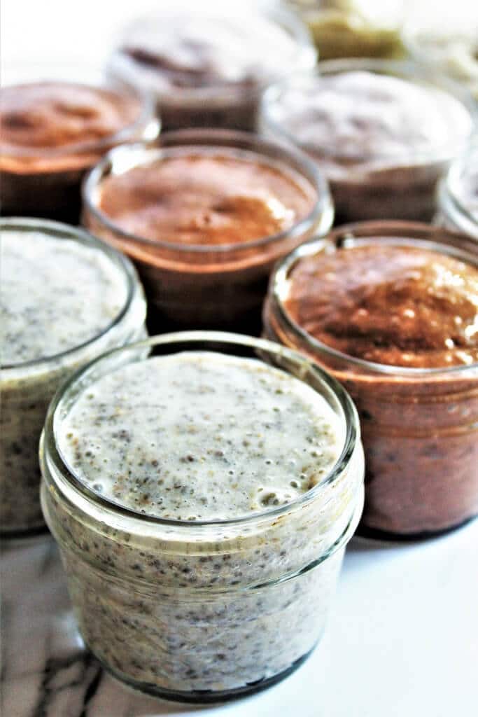 Many vanilla and chocolate chia puddings in mason jars ready to store in the fridge. 
