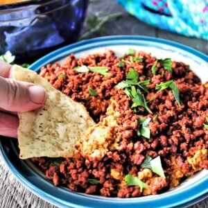A chip being dipped into soy chorizo dip.