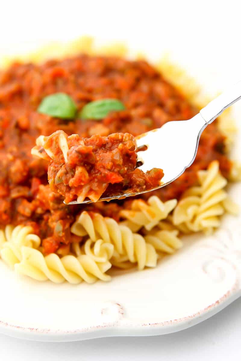 A fork full of vegan pasta sauce served over spiral pasta.