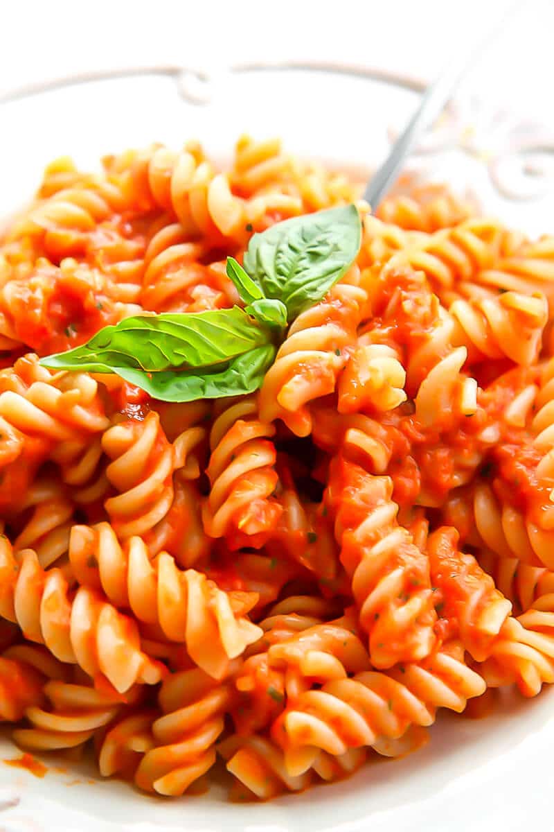 A close up of a plate of pasta with oven roasted tomato sauce on it.