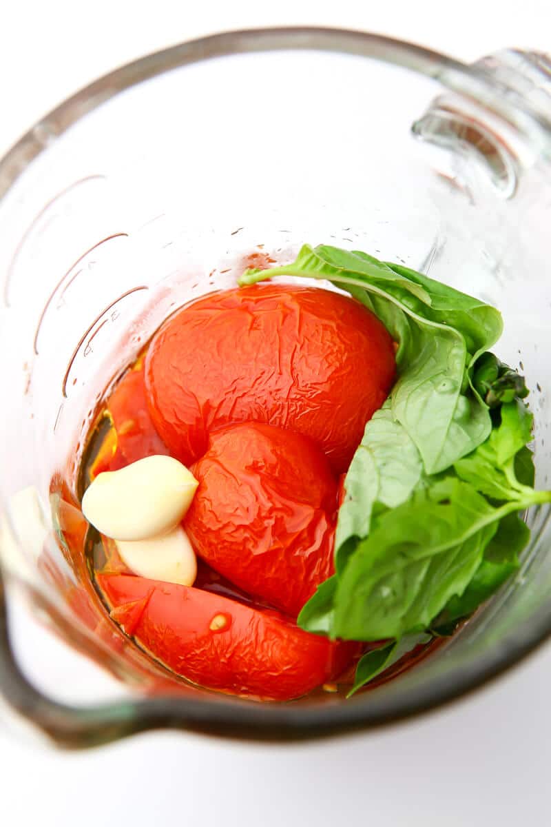 Roasted tomatoes in a blender with garlic, basil and olive oil before blending.