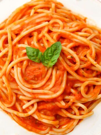 A top view of a white plate filled with homemade oven roasted tomato sauce over pasta.