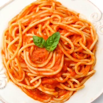 A top view of a white plate filled with homemade oven roasted tomato sauce over pasta.
