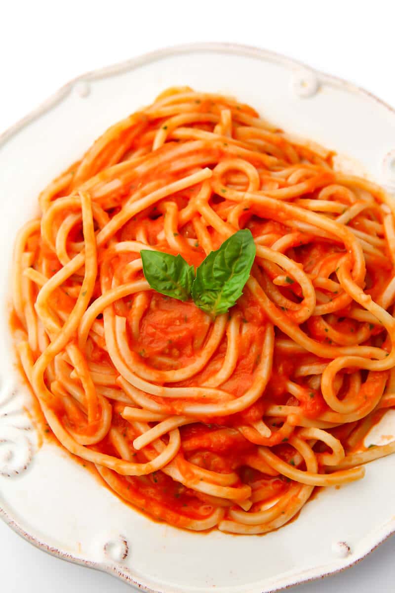 A top view of a plate filled with spaghetti with roasted tomato sauce.
