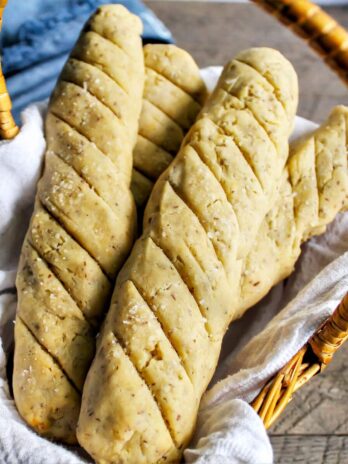 A bread basket with 4 gluten-free vegan breadsticks with a blue napkin behind it.