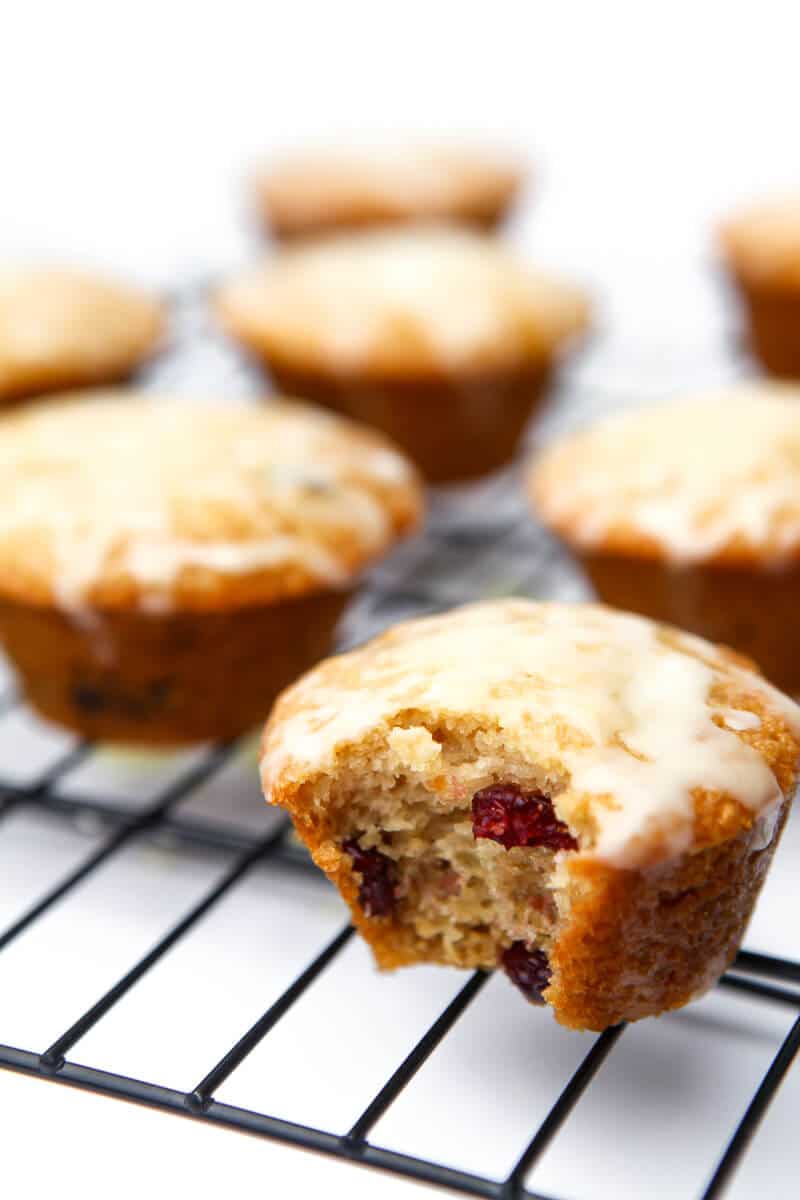 Cranberry orange muffins on a cooling rack with a bite taken out of 1 of them.