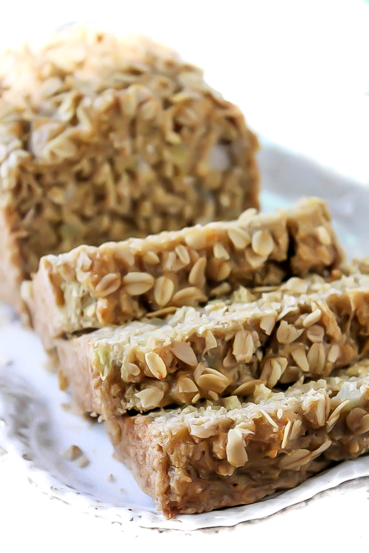 A loaf of sliced vegan beer bread with oats sprinkled on top.