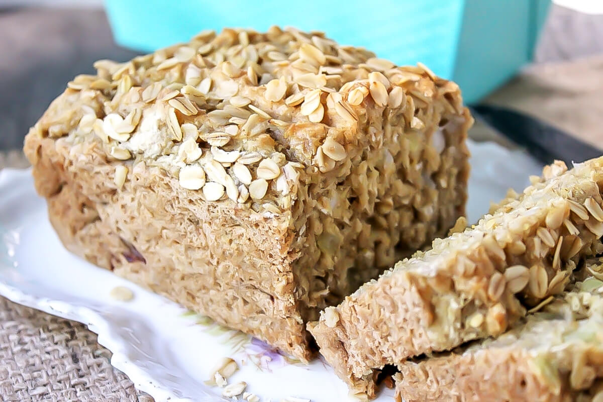 A loaf of easy vegan beer bread sliced with oats on top.