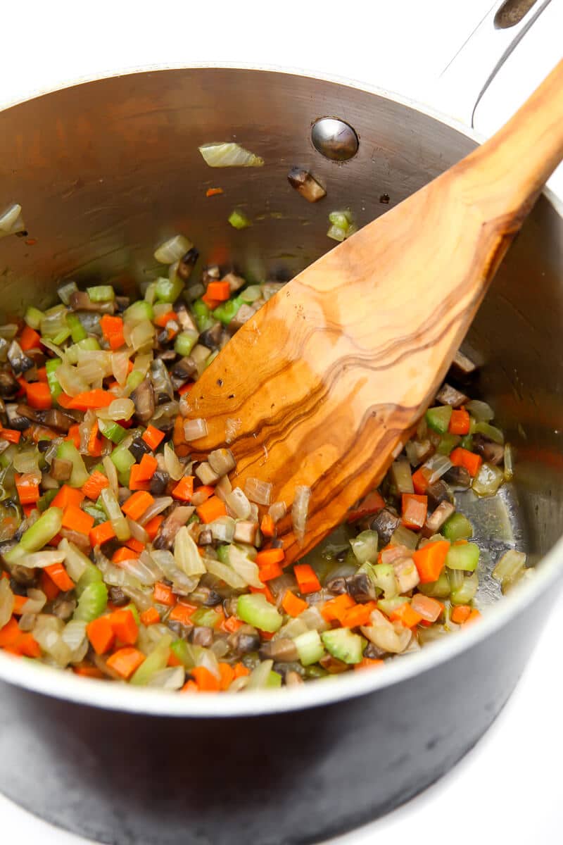 Onions, carrots, celery, and mushrooms sautéing in vegan butter.