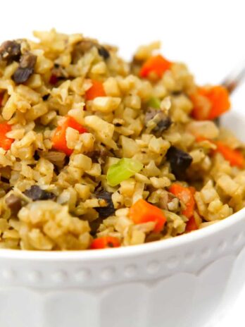 A close up of a bowl of cauliflower stuffing made with carrots, mushrooms, celery, and riced cauliflower.