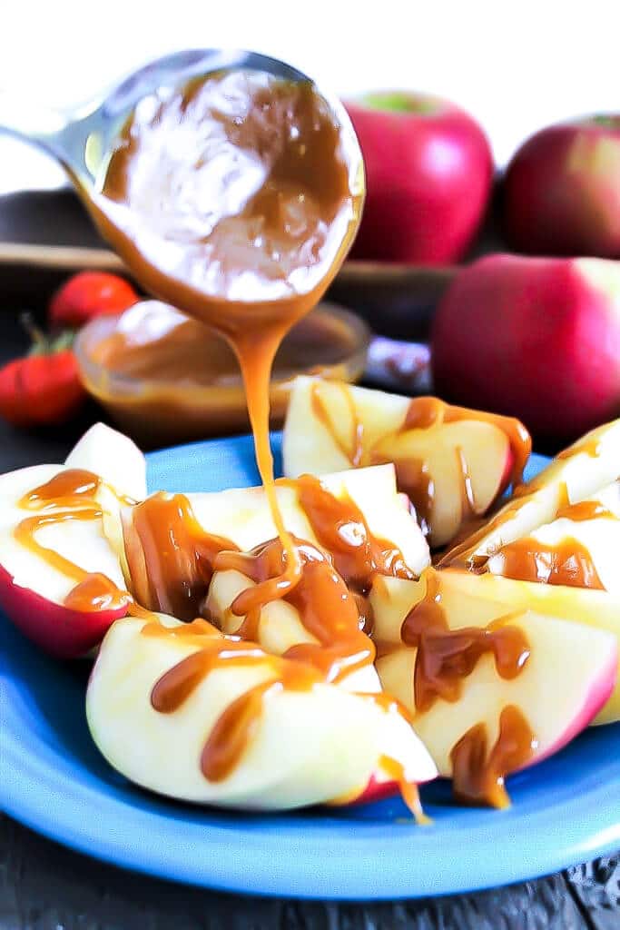 A plate of apple slices drizzled with vegan salted caramel sauce.