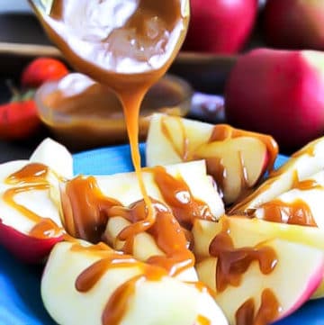 A blue plate with sliced apples with vegan salted caramel sauce being poured over the apples.