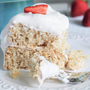 A close up of a slice of vegan angel food cake with vegan whipped cream on top.