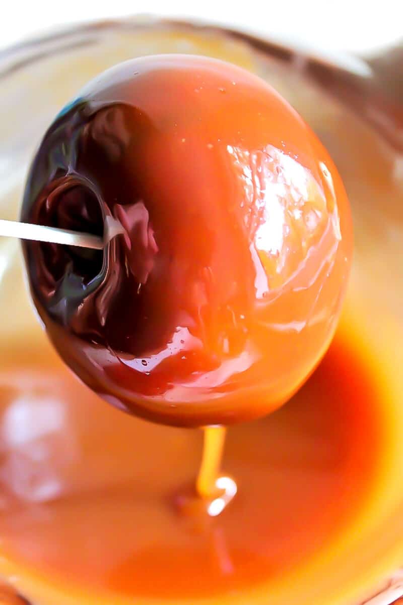 An apple dipped in vegan caramel to make vegan caramel apples.