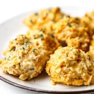 A white plate filled with golden vegan Red Lobster Biscuits.